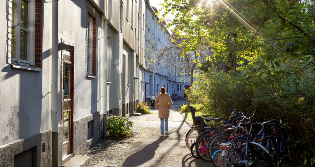 Kvinna går på gångstråk längs husfasader.