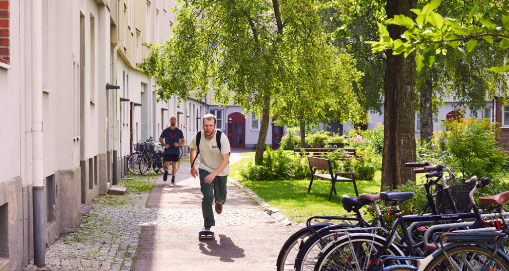 Kille åker skateboard på en lummig innergård.