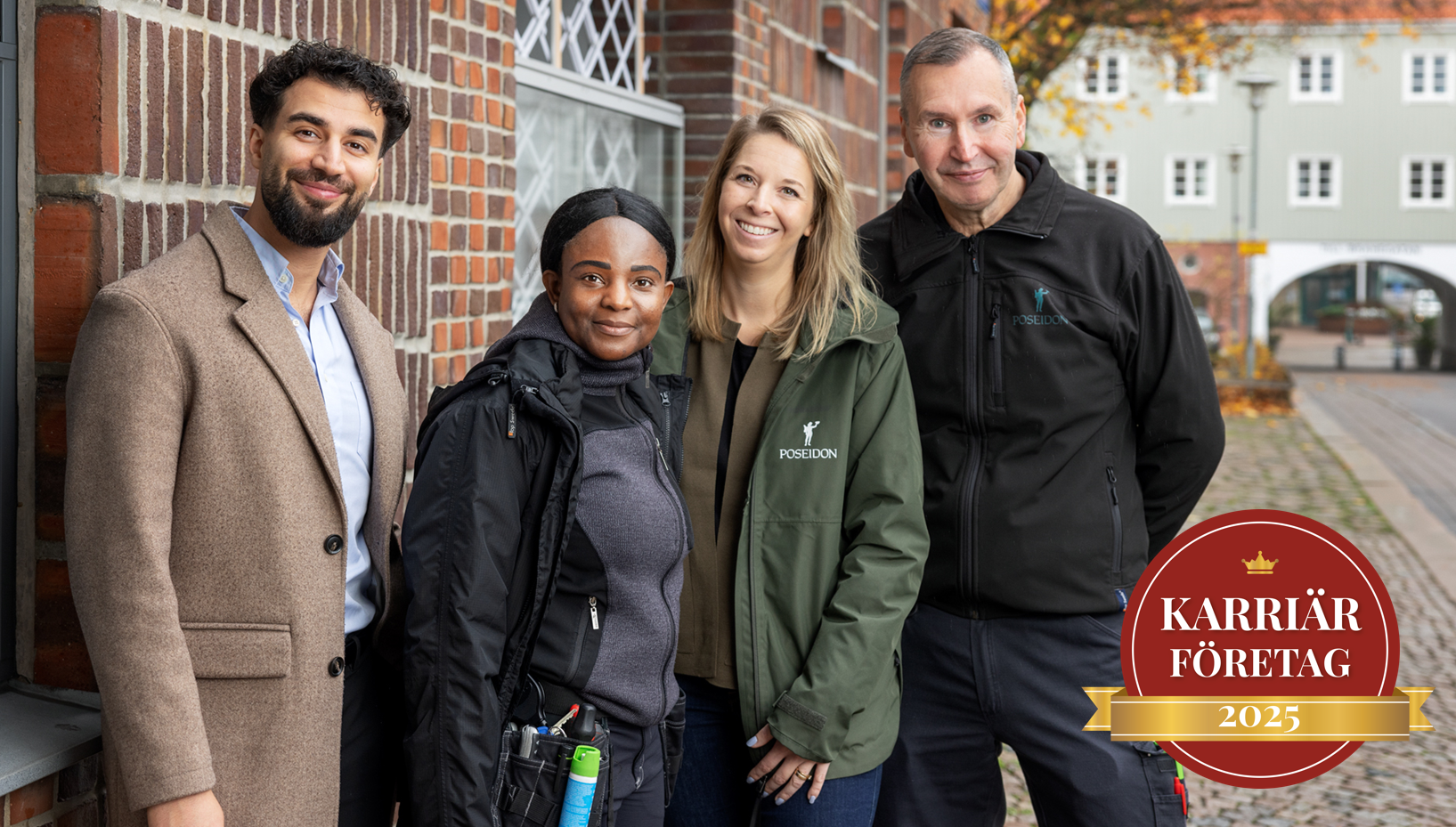 Fyra glada kollegor, en i ullkappa, en i arbetskläder, en i Poseidons gröna tjänstemannajacka, en i arbetskläder. Bakgrund ett fint tegelhus och längre bort ett landshövdingehus.