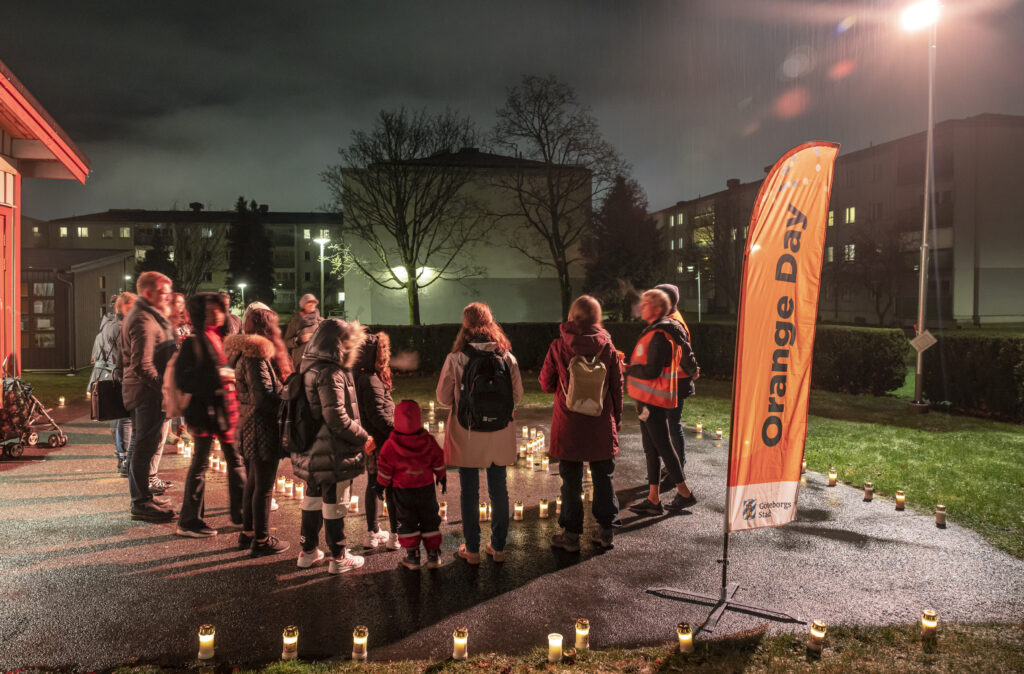 Kvällsbild med människor vid en vimpel med texten Orange Day.