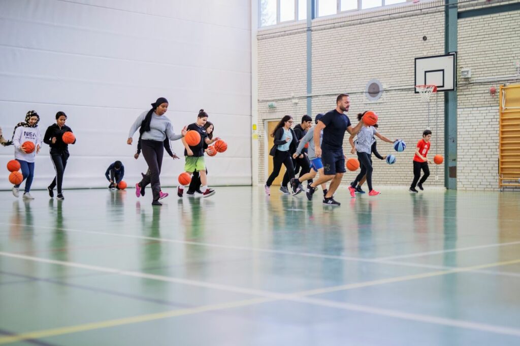 ungdomar studsar basketboll i gympahall