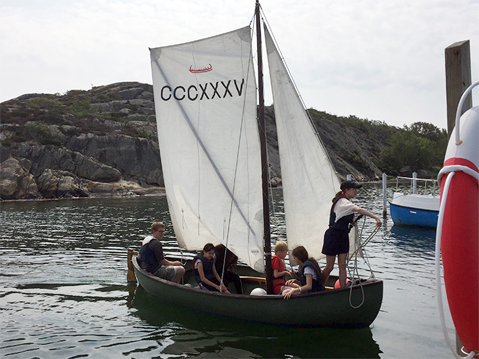 Sex barn i färd med att förtöja en gammaldags segelbåt