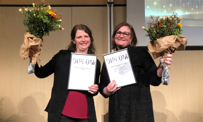 Två glada vinnare med diplom och blomsterkvastar i händerna
